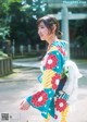 A woman in a colorful kimono standing in front of a gate.