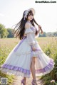 A woman in a white and purple dress standing in a field.