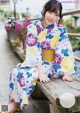 A woman in a kimono sitting on a wooden bench.