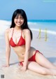 A woman in a red bikini sitting on the beach.