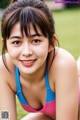 A woman in a pink and blue bikini laying on the grass.