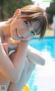 A young woman sitting on the edge of a swimming pool.