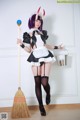 A woman dressed as a maid holding a broom.