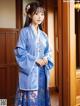 A woman in a blue hanbok standing in front of a door.