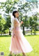 A woman in a pink dress standing in a field.