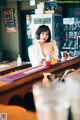 A woman sitting at a bar in a white shirt.