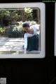 A woman sitting on the ground looking out of a window.